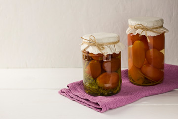 Canned tomatoes in glass jar on a white background