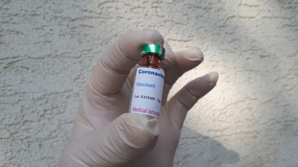 Ampule with coronavirus SARS-CoV-2 vaccine in hand with glove