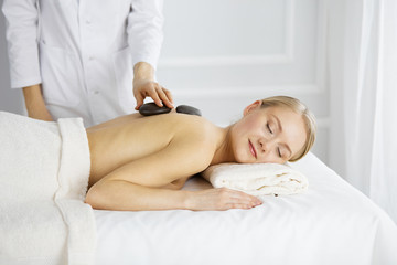 Beautiful caucasian woman enjoying warm stones procedure with closed eyes. Beauty and Spa salon concept
