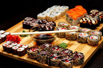 Tasty and delicious hot and cold sushi rolls on the table. Different sushi - rolls with sauce on the board of Japanese cuisine.