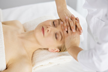Beautiful caucasian woman enjoying facial massage with closed eyes in spa salon. Relaxing treatment in medicine and Beauty concept