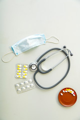 On a gray table is a medical mask, a stethoscope and medicines concept.