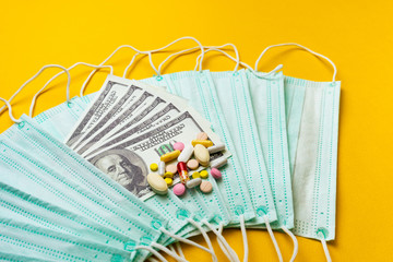Sale of medical masks. Protective medical mask and different types of pills next to money on yellow background. Coronavirus concept. 2019 nCoV.