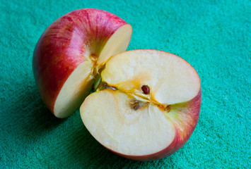Two halves of a red Apple on a green napkin.