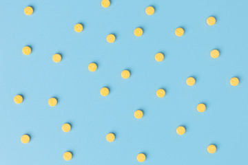 Yellow medical pills on blue background with copy space.