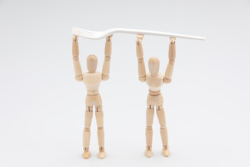 Wooden dummies carrying a biodegradable fork in front of a white background
