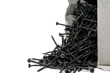 a bunch of new metal black screws poured out of the box on a white background.