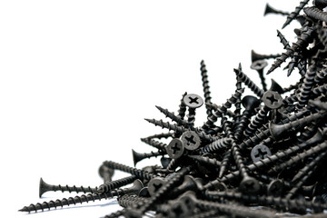 a bunch of new metal black screws poured out of the box on a white background.