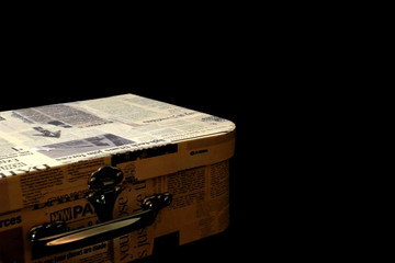 Suitcase with newspaper labels on a black background.