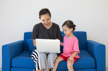 Mother is teaching her child to use a laptop to learn about the digital world, which is an opportunity to spend time together, for families working at home or doing business through online trading.