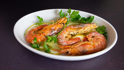 roasted prawns with lemon slices in white baking dish 