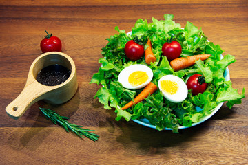 Tasty fresh mix vegetable salad on white dish and wooden plate.
