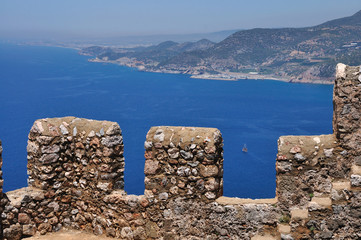 Beautiful view of the clear blue sea from the high mountain. There 's a fortress wall on the mountain.