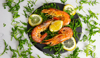 roasted prawns with lemon slices on a slate plate and white background