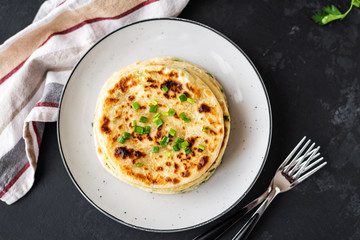 Chinese green onion pancakes on a black background. Stack of fried green onion pancakes. Dark photo