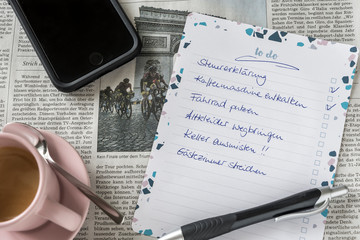 Handwritten german to-do list, coffee and mobile phone on newspaper