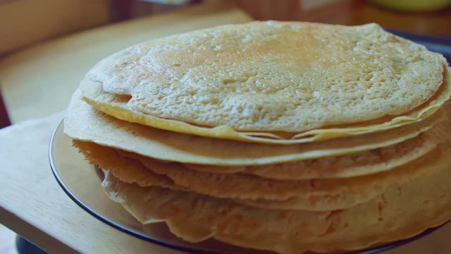 Yellow delicious pancake stack on brown plate. Home cooking. Slowmo. Side view.