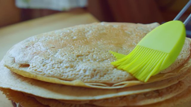 Cook smear pancake oil brush on plate in kitchen. Slowmo clouseup. Side view.