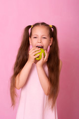 A beautiful portrait of a little girl who eats a green apple.