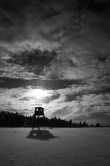 myśliwska ambona na tle zachodzącego słońca zimą