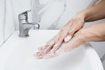 Young man washing hands over sink in bathroom, closeup, Corona virus or Covid-19 prevention, hygiene to stop.