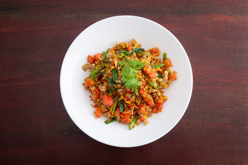Homemade Scrambled eggs with carrots and tomatoes in white plate on wooden table.