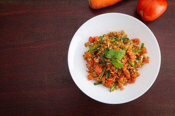 Homemade Scrambled eggs with carrots and tomatoes in white plate on wooden table.