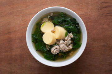 Boiled minced pork and tofu soup with gourd in white bowl on wooden table, Thai food, Healthy food.