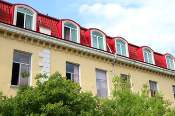 Ornate building with opened windows behind green foliage for STAY-AT-HOME concept