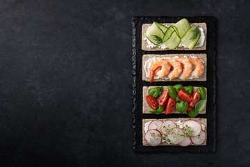 Different kinds of colorful sandwiches on a black background. Top view, place for text.
