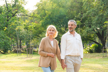 Naklejka na ściany i meble portrait of man and woman holding hand and walking at park, Love marriage lifestyle goals, Happy retirement senior couple spending time, talking, sharing and relaxing together, life insurance concept 