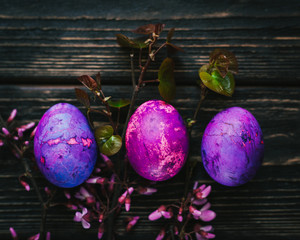three purple easter eggs on dark wooden background