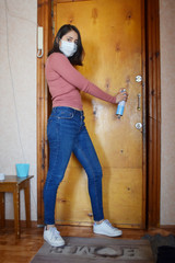 Fototapeta premium young woman wearing face mask with disinfectant spray pointing at door