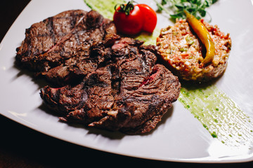 Stock Photo - Ribeye steak with vegetable dressing on a white plate