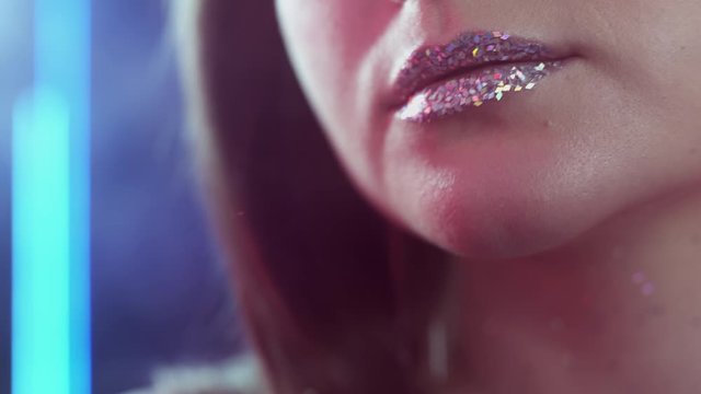 Glitter makeup portrait. Aesthetic cosmetology. Sensual woman sparkling lips in red lights.