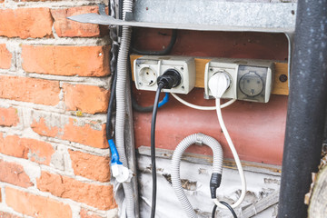 old electrical plugs in outlets on the street, unsafe use of electrical outlets