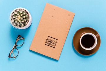 Flat lay with box package for sending, coffee cup, eyeglasses and cactus on blue background. Sending or receiving goods. Shipment and delivery concept.