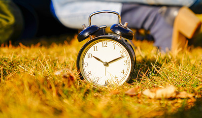 Image of spring Time Change. Summer back concept. Vintage alarm Clock outdoors. alarm clock on green grass 