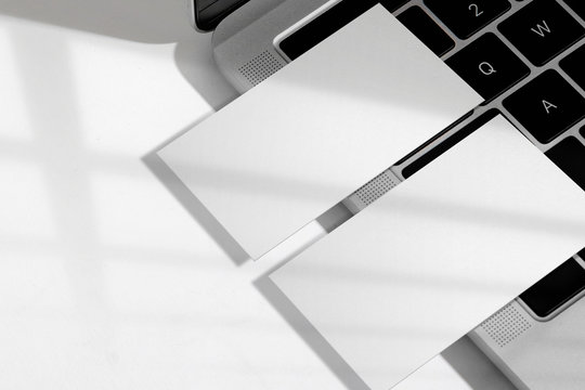 Clean minimal white business card mockup on laptop and white background.