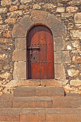 Fototapeta na wymiar old wooden door with metal fittings in a stone building creating a background with stairs