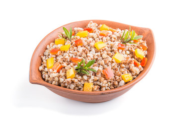 Fototapeta na wymiar Buckwheat porridge with vegetables in clay bowl isolated on white background. Side view, close up.