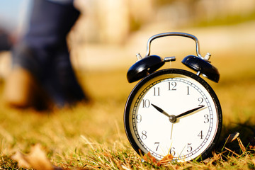 Image of spring Time Change. Summer back concept. Vintage alarm Clock outdoors. alarm clock on green grass 