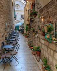 SIBENIK, CROATIA - 2017 AUGUST 18. Narrow walking path with chairs and tables outside the old city of Sibenik.