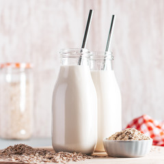 Non dairy oat milk in glass jars with reusable metal straws. Healthy vegan milk alternative still life, copy space. Substitute for traditional cow milk with oat flakes, healthy lifestyle concept