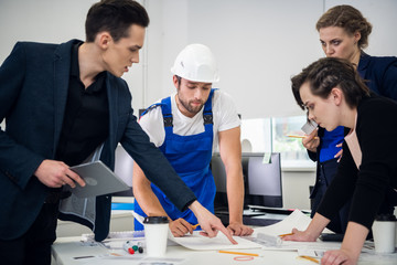 Two successful businesswomen and two businessmen around the desk, discussing new projects