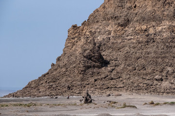Two children walking next to a rock formation in lake Abbe salt desert