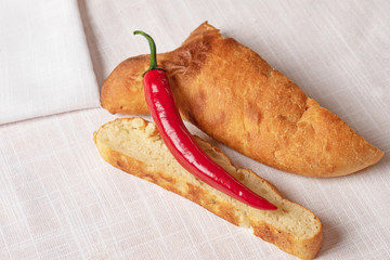chili pepper and a slice of homemade bread on a white tablecloth in isolation. Minimalism in food background