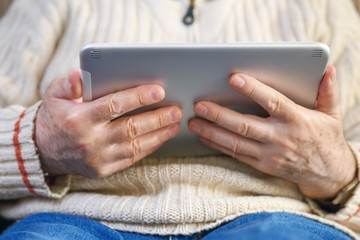 Close up Portrait of senior man sitting on sofa and using digital tablet in living room .
