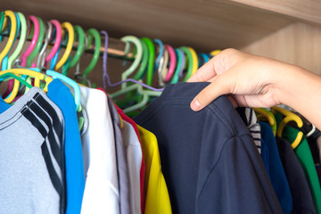 Obraz premium Hand choosing clothes to wear in wardrobe.