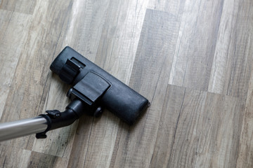 Dark head of a modern vacuum cleaner on wood floor